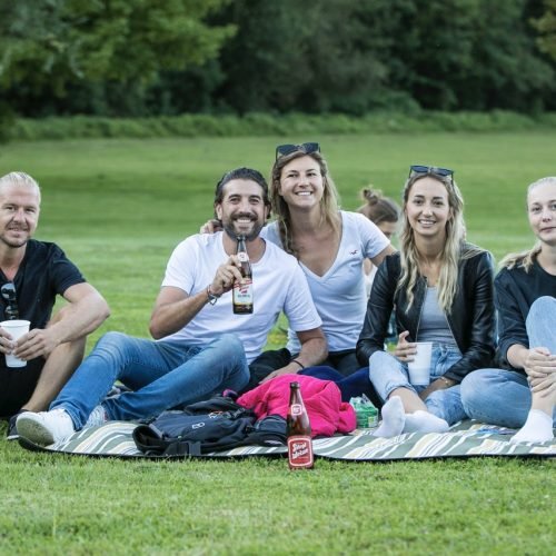 Gruppenfoto von Freunden, die in einer Wiese beim Sommerkino am Salzachsee sitzen
